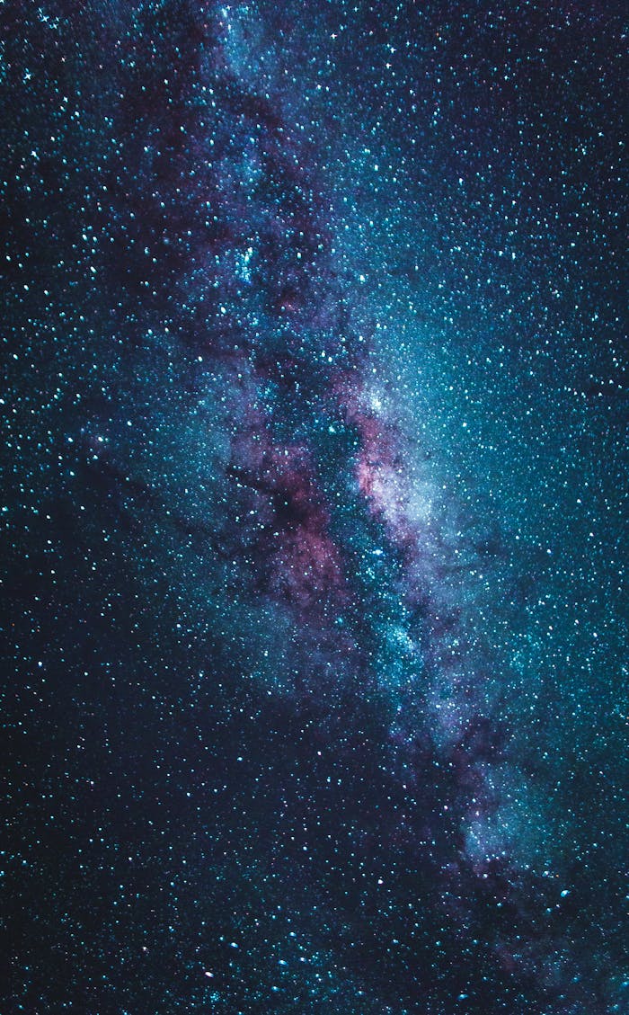 Stunning vertical view of the Milky Way galaxy in blue and purple hues under a starry night sky.
